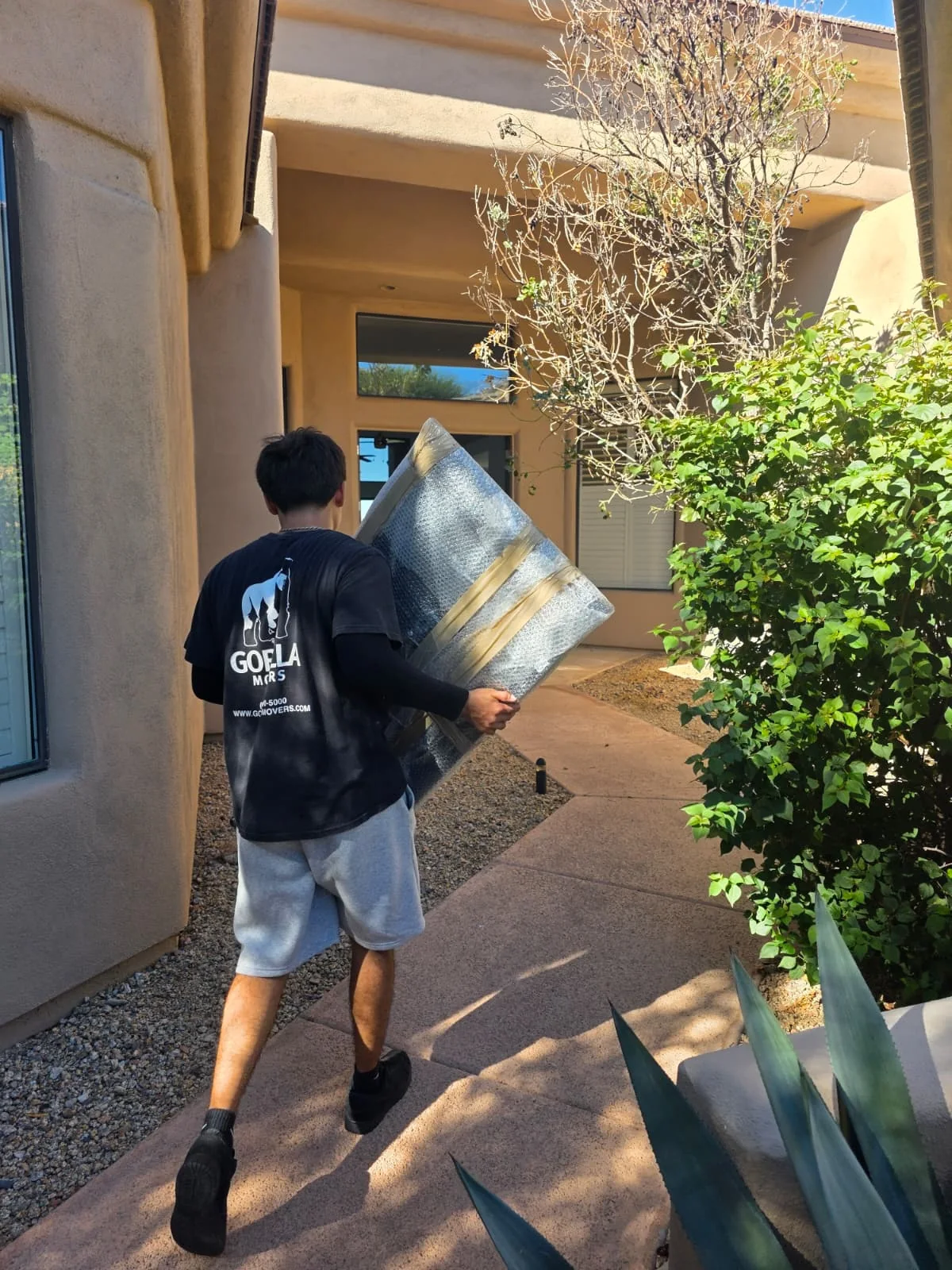 Gorilla Movers crew member carrying a bubble-wrapped mirror into a home on a Phoenix, Arizona move