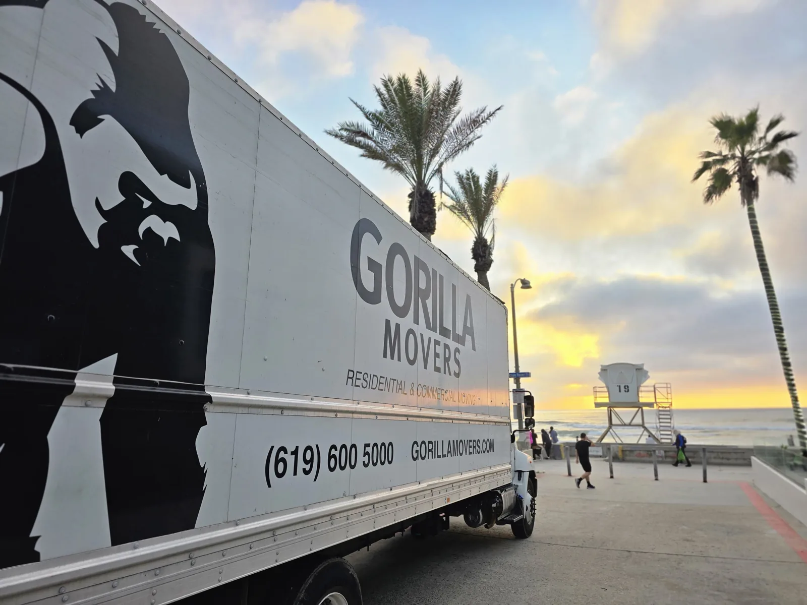 Gorilla Movers truck parked at the beach in San Diego at golden hour, lifeguard tower behind